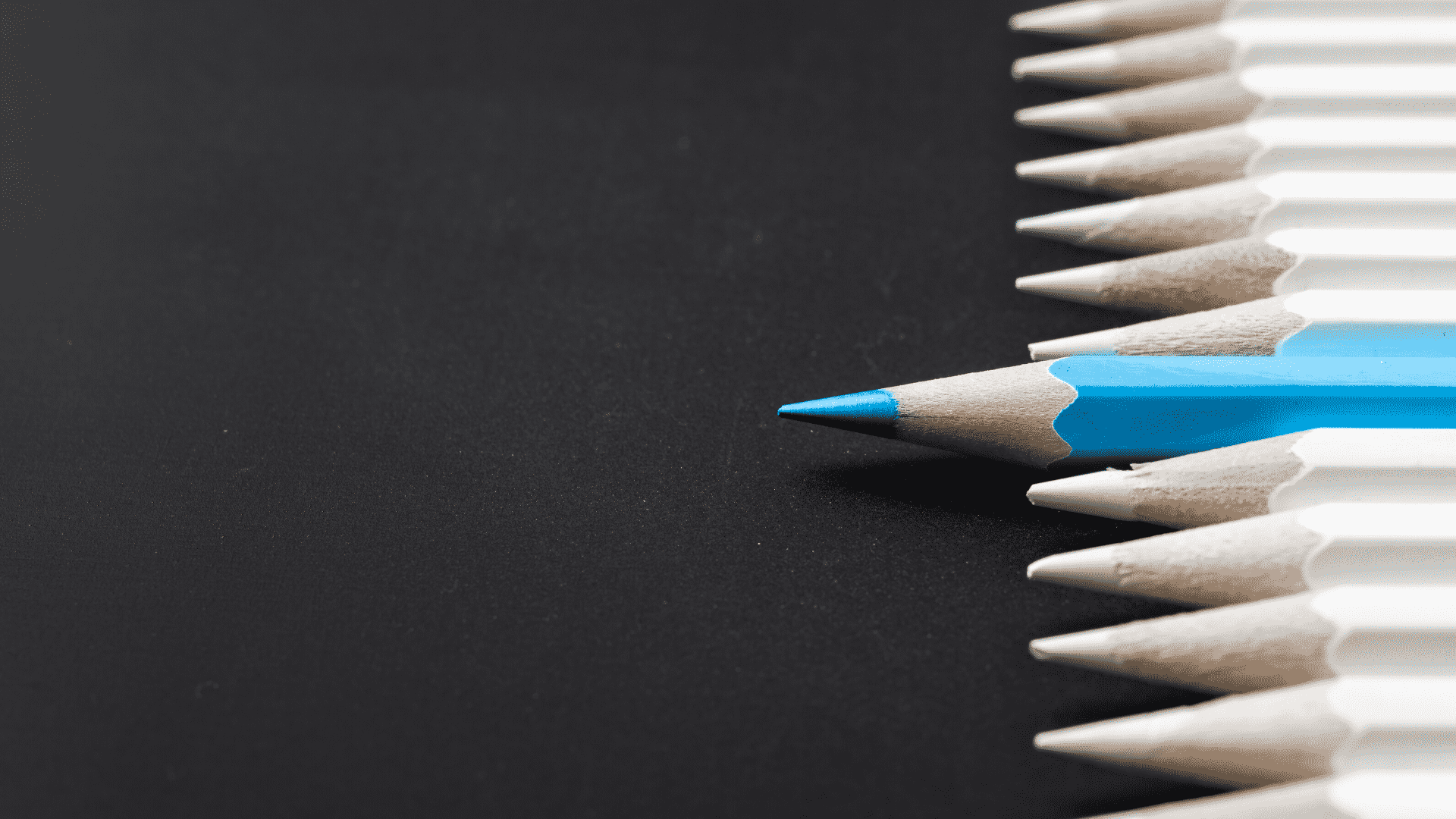 row of pencils with blue pencil sticking out 