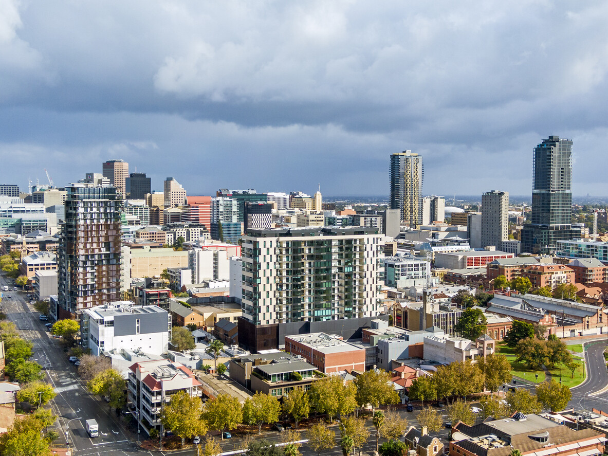 City skyline of South Australian city, Adelaide with tall buildings and trees in the foreground.
